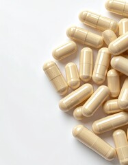A pile of light beige capsules rests on a stark white background, scattered casually