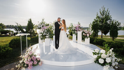 The bride and groom at the wedding ceremony site, decorated with flowers
