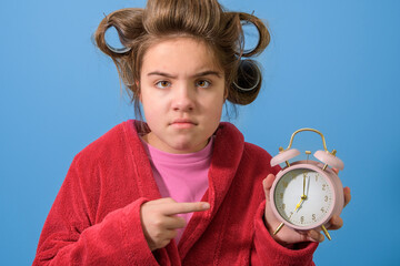 Teenager angry at alarm clock early in the morning. Ironic portrait. switching clocks to winter time. fall back