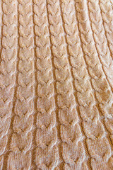 Full frame of beige knitted wool sweater with a classic cable knit pattern. Warm cozy fabric background for winter clothing, handmade knitwear, hygge lifestyle, and textile design concepts. Perfect