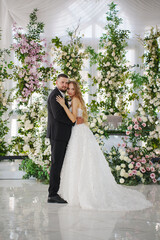 Beautiful bride and groom on the background of flowers in the decor.