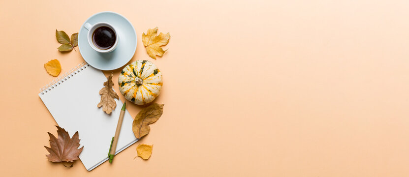 Autumn composition: fallen leaves and notebook mock up on colored background. Top view. Flat lay with copy space