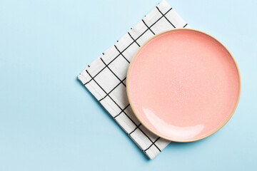 Top view on colored background empty round pink plate on tablecloth for food. Empty dish on napkin with space for your design