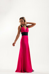 Fototapeta premium Woman posing in a vibrant pink gown with black accents against a simple backdrop