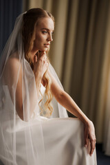 The bride in simple beautiful elegant wedding dress sitting on a chair