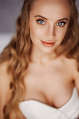 Sensual portrait of a sexy blonde young woman in a white off-the-shoulder dress.