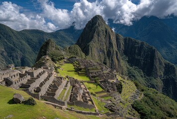 High-angle shot of Machu Picchu ruins surrounded by green grass, mountains, and a cloudy sky, on a sunny day