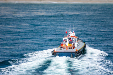 A pilot boat navigates the waters off Mejillones, Chile, heading towards a cargo ship. 