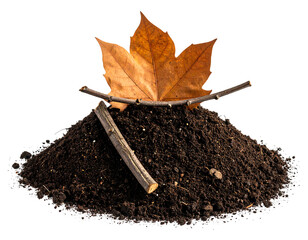Pile of dark brown earth with fallen autumn leaf and twigs atop