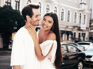 Naklejka premium Smiling beautiful woman and her handsome boyfriend. Happy cheerful family. Sexy couple posing in the street at sunrise. During romantic date at sunny summer day outdoors. Looking at each other