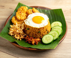 Fragrant fried rice with sunny-side egg, crispy chicken, cucumber slices, and spicy chili garnish.