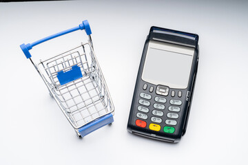 Blue shopping basket, payment terminal, shopping experience. A payment terminal for plastic cards and a shopping cart, the idea of paying with bank cards at the checkout. High quality photo