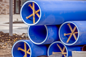 Plastic water pipes are stacked on a construction site on an autumn day