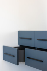 Blue floating cabinet. Open drawers. Clean space.
