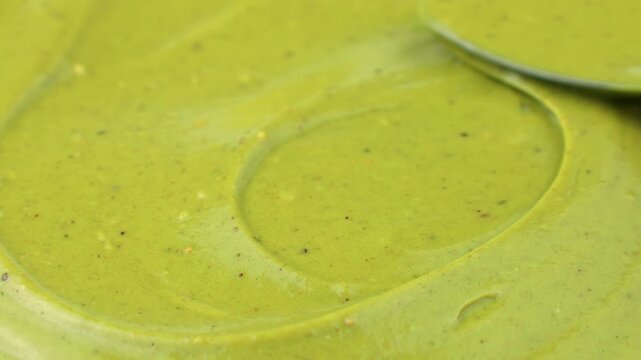 Green homemade pistachio paste spreading and taking with a spoon close up