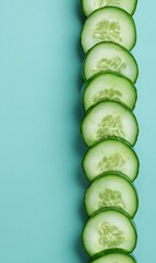 Fresh green cucumber slices arranged in a neat vertical row on a bright turquoise background