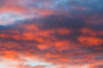 Breathtaking natural background of a dramatic sky with fiery red and dark clouds during a vibrant sunset or sunrise.
