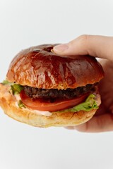 Freshly sliced burger! This close-up shows hands holding a delicious burger cut in half, revealing its juicy patty and fresh ingredients. Perfect for fast food, menu, and cooking concepts. Appetizing 