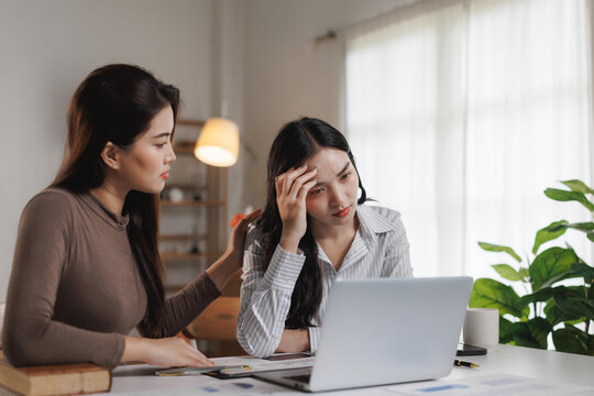 Asian businesswomen comforting stressed colleague in office