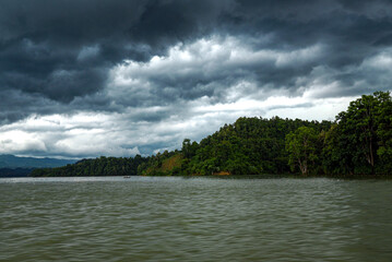 Stormy Lake Landscape Under Heavy Clouds Over Calm Water and Forested Shoreline
