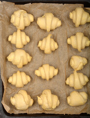 An overhead close-up of raw, rolled croissant dough pieces arranged on parchment paper before baking