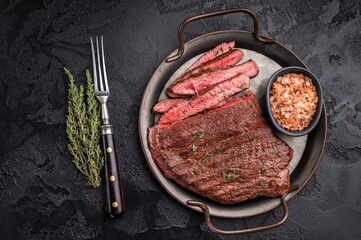 Succulent grilled top sirloin steak, cooked to perfection and drizzled with a rich sauce for an unforgettable dining experience. black background. top view