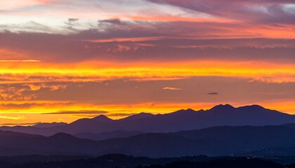 Vibrant sunset hues paint the sky above a silhouetted mountain range