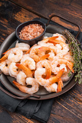 A plate of shrimp with a black bowl of salt and pepper. The shrimp are arranged in a way that they look like they are ready to be eaten