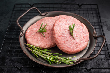 Freshly formed raw meat patty with herbs for burgers, perfect for grilling or frying to satisfy your cravings. black background. top view