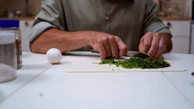 A chef professionally prepares a fresh vegetable salad, chopping potatoes, eggs, and greens. Dynamic cooking process showcasing culinary skills and healthy food preparation
