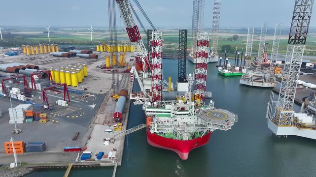 Rotterdam, Netherlands. Drone flight over industrial area with cargo ports, containers and a semi-submersible ship, heavy lifting crane. Machines designed for work at sea
