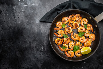 Fried Shrimps Prawns with garlic and butter in a skillet. Black background. Top view