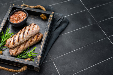 Roasted on BBQ beef and lamb sausages in wooden tray. black background. top view