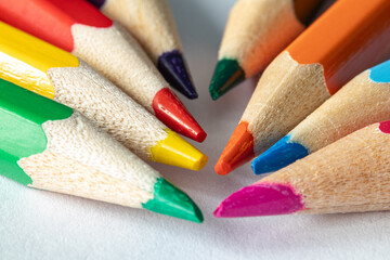 Fototapeta premium Close-up of sharpened colored pencils arranged in a radial pattern. Bright rainbow colors on white background. Macro composition