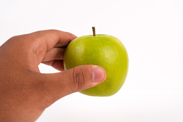 A person's hand is holding a whole, freshly picked green apple on a white background.