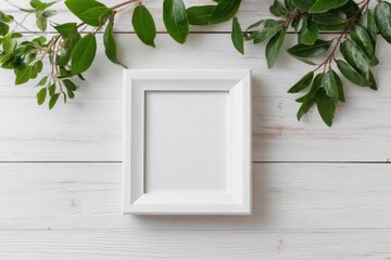 White picture frame on a white wooden surface, surrounded by green foliage