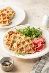 Zucchini waffles served with arugula salad and prosciutto. Healthy vegeterian savory breakfas
