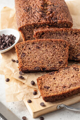 Chocolate zucchini bread cake sliced close up. Moist chocolate cake with grated zucchini, cocoa powder and chocolate chips on white tile kitchen background