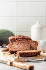 Chocolate zucchini bread cake sliced. Moist chocolate cake with grated zucchini, cocoa powder and chocolate chips on white tile kitchen background