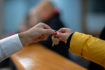Detail of two people exchanging keys at a reception desk, symbolizing check in, service,...