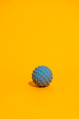 Blue spiky massage ball on bright orange minimal fitness recovery concept with copy space. High quality photo