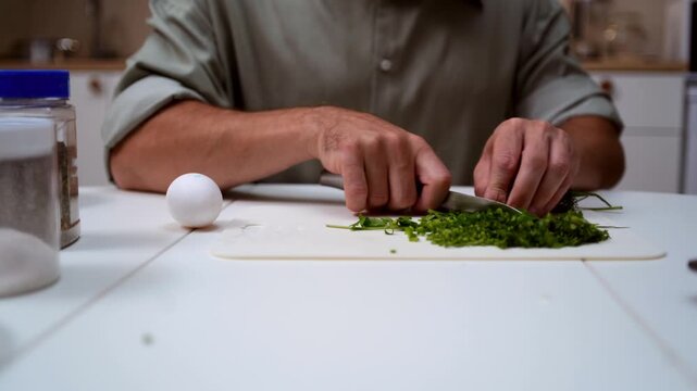 A chef professionally prepares a fresh vegetable salad, chopping potatoes, eggs, and greens. Dynamic cooking process showcasing culinary skills and healthy food preparation