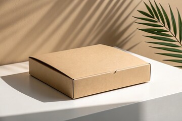 A simple, unadorned cardboard box mockup on a white surface, complemented by a green leaf and warm-toned wall, a minimalist aesthetic.