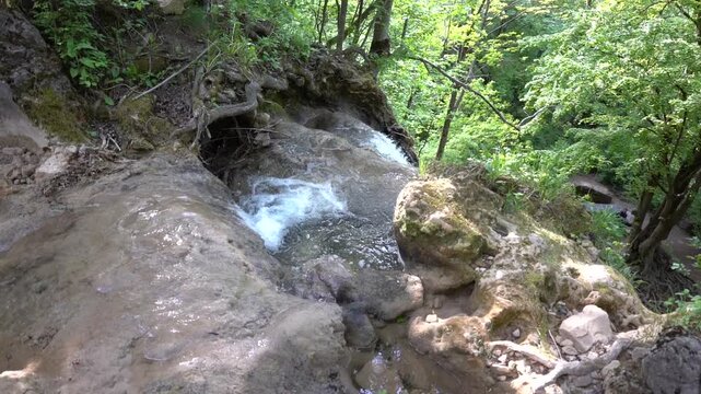 A waterfall on a mountain stream, the edge of a waterfall from where the water begins to fall. The camera makes a crane movement down to the edge of the waterfall. Blederija waterfall, Ozren mountain