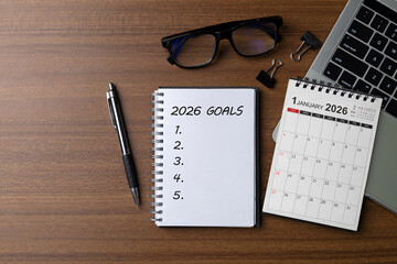 Notebook titled 2026 Goals with a blank checklist and mini calendar, pen, glasses and laptop on a desk, illustrating life and business goal planning, strategy, productivity and a fresh start.