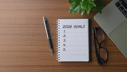 Notebook titled 2026 Goals with a blank checklist and January 2026 calendar, pen, glasses and laptop on a desk, illustrating life and business goal planning, strategy, productivity, and future roadmap