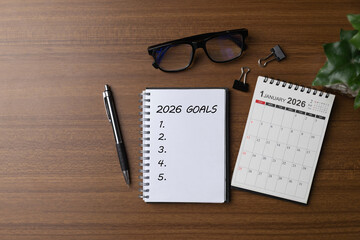 Notebook titled 2026 Goals with a blank checklist beside a January 2026 calendar, pen and glasses on a desk, symbolizing life and business goal planning, strategy, productivity, and a fresh start.