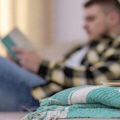 stack of teal towels with young man reading on sofa