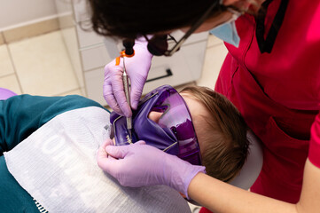 Young patient receiving dental care while wearing protective eyewear in a bright clinic setting during a routine check-up