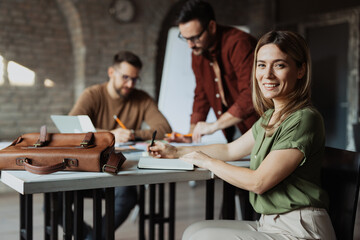A group of young enthusiastic professionals working together in a bright modern office. They are creating a business plan, sharing ideas, and collaborating on a startup project
